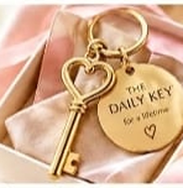 Gold heart-shaped key with a round gold disc engraved The Daily Key for a lifetime