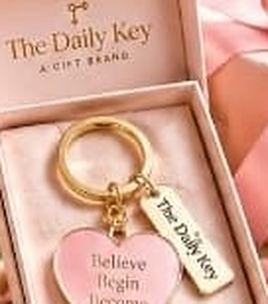 Blush heart charm reading Believe Begin Become with a gold The Daily Key tag, in a pink box