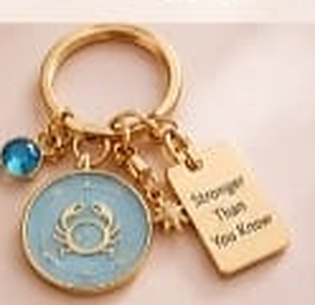 Cancer zodiac keychain with a gold ring, enamel sign disc, crystal, star charm and tag reading Stronger Than You Know
